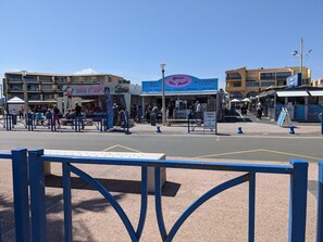 Een straatbeeld met een café genaamd Glacier Chez Pierrot, een babywinkel en een kiosk.