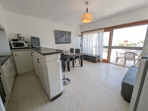 A compact kitchen with a microwave, a small refrigerator, and a dining area with a table and chairs.