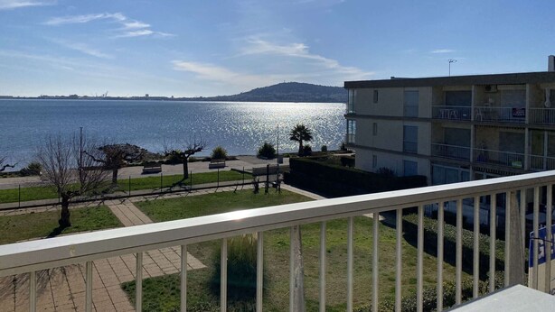 Ein Balkon mit Blick auf ein ruhiges Meer und sanfte Hügel in der Ferne.
