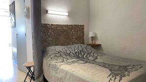 Ein Schlafzimmer mit einem Bett, einem Nachttisch, einer Lampe, einem Sessel und einer Wand mit strukturierter Oberfläche.