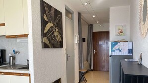 Ein schmaler Flur mit einer Küchenzeile, die Schränke, ein Spülbecken und ein dekoratives Wandelement umfasst.