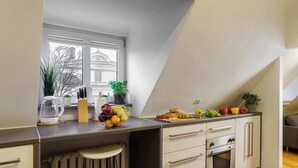 Een moderne keuken met een groot raam, een ingebouwde oven en een aanrecht met diverse etenswaren en keukengerei.