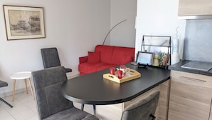 Eine moderne Küche mit schwarzem Arbeitsplatz, einem roten Sofa und einem Essbereich mit zwei grauen Stühlen.