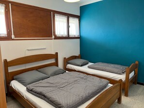Una habitación con dos camas de madera, cada una con una almohada y una colcha a cuadros.