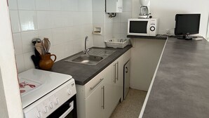 Une cuisine de taille réduite équipée d’une cuisinière, d’un four à micro-ondes et d’un évier.