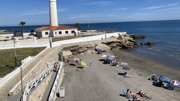 Una zona costiera con un faro, una spiaggia e un litorale roccioso.