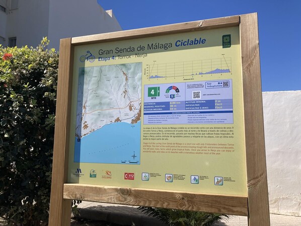 A signboard for the Gran Senda de Málaga cycling route, detailing the 4th stage from Torrox to Nerja, including a map, distance, altitude, and difficulty level.