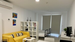 A modern living room with a yellow sofa, a white coffee table, a white TV stand, and a bookshelf. - Beachfront apartment with air conditioning and Wi-Fi in Torrox-Costa (Torrox Costa)