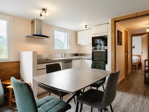 A modern kitchen with a dining area, built-in appliances, and a view of the outdoors.