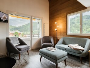 A modern living room with a sofa, chairs, and a wooden floor.
