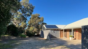 A building with a covered outdoor area, a fenced yard, and trees.