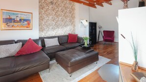 Ein modernes Wohnzimmer mit einem braunen Ledersofa, einem roten Sessel und einem Holztisch.
