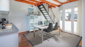 Eine moderne Küche mit Einbauherd, Spüle und einer Frühstückstheke. Eine Treppe führt zu einer oberen Ebene.
