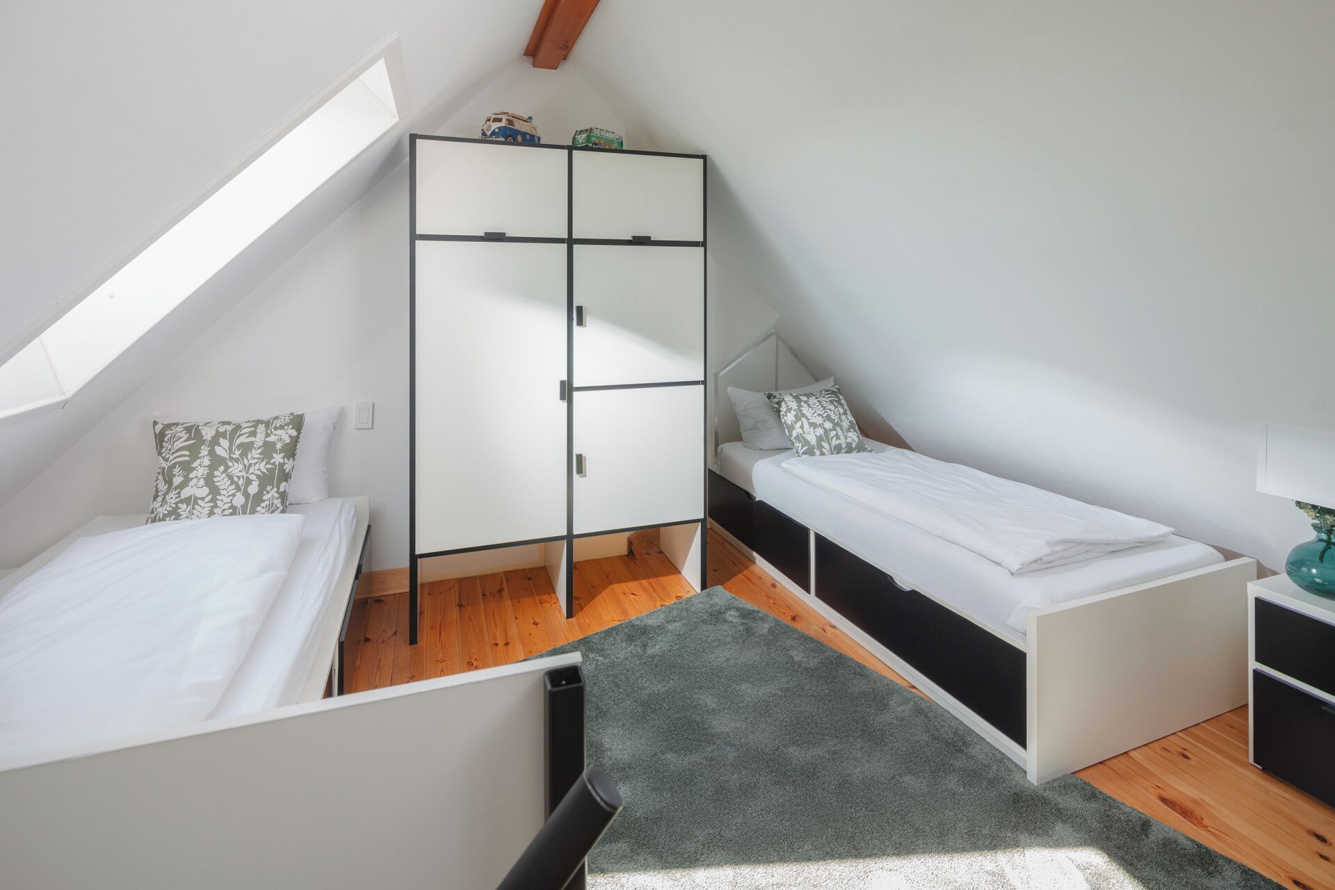 A small, modern bedroom with a loft-style bed, a wardrobe, and a desk.