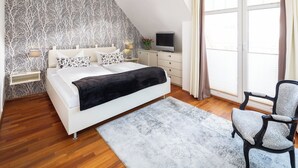 Ein modernes Schlafzimmer mit einem Bett, Nachttischen, einem Fernseher und einem Sessel.