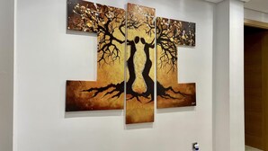 Ein Flur mit drei großen Bildern an der Wand, die einen Baum mit Wurzeln und eine menschliche Gestalt zeigen.
