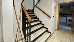 Eine Treppe mit schwarzen Geländern und Holzhandläufen, die zu einer oberen Etage führt.