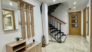 Ein Flur mit einer Holztreppe, einem Spiegel und einer Holzkommode mit Pflanzen.