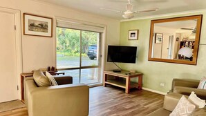 A living room with a sofa, TV, and a large mirror. - Lazy Sails Starboard  - Pets welcome outside, WiFi (Robe)