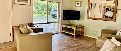 Un soggiorno con un divano, una TV e un grande specchio.
