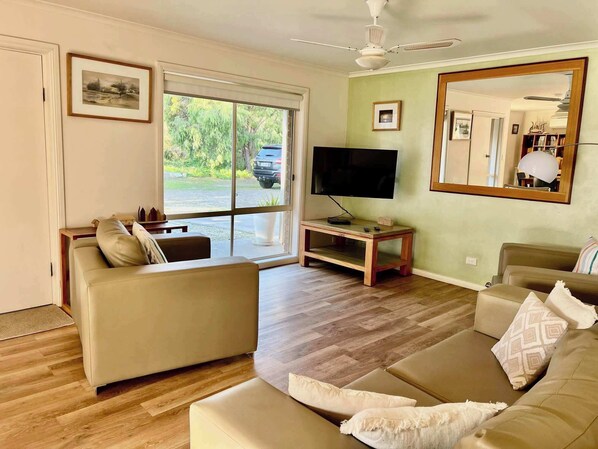 A living room with a sofa, TV, and a large mirror. - Lazy Sails Starboard - Pets welcome outside, WiFi (Robe)