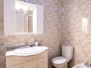 A bathroom with a marble sink, a toilet, and a mirror above the sink.