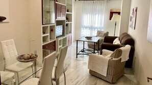 A modern living room with a glass dining table, a sofa, and a TV. - Charming Apartment with Pool & Garage in Córdoba's Prime Shopping District (Córdoba)