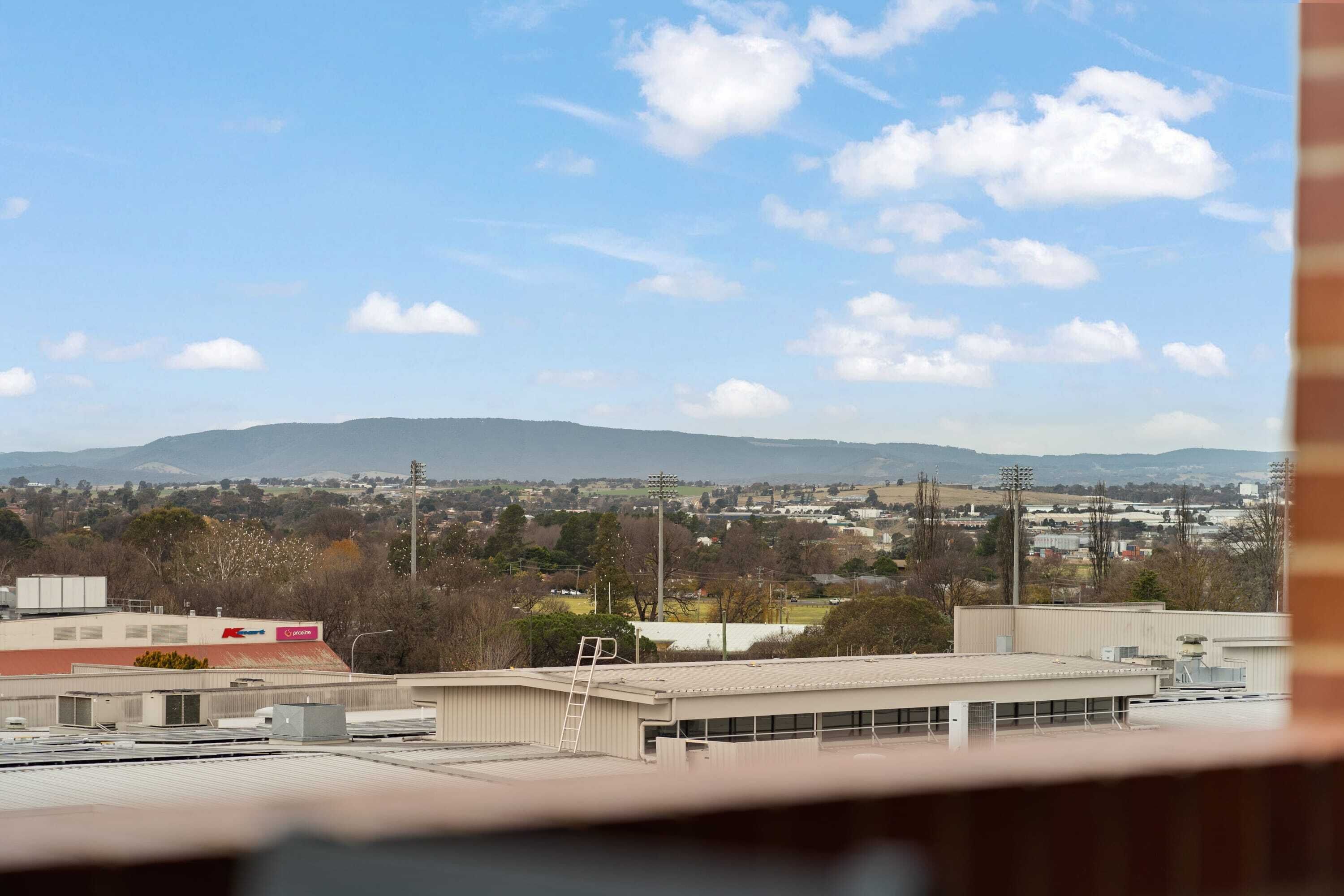 A view of a cityscape with buildings, a ladder, and a distant mountain range.
