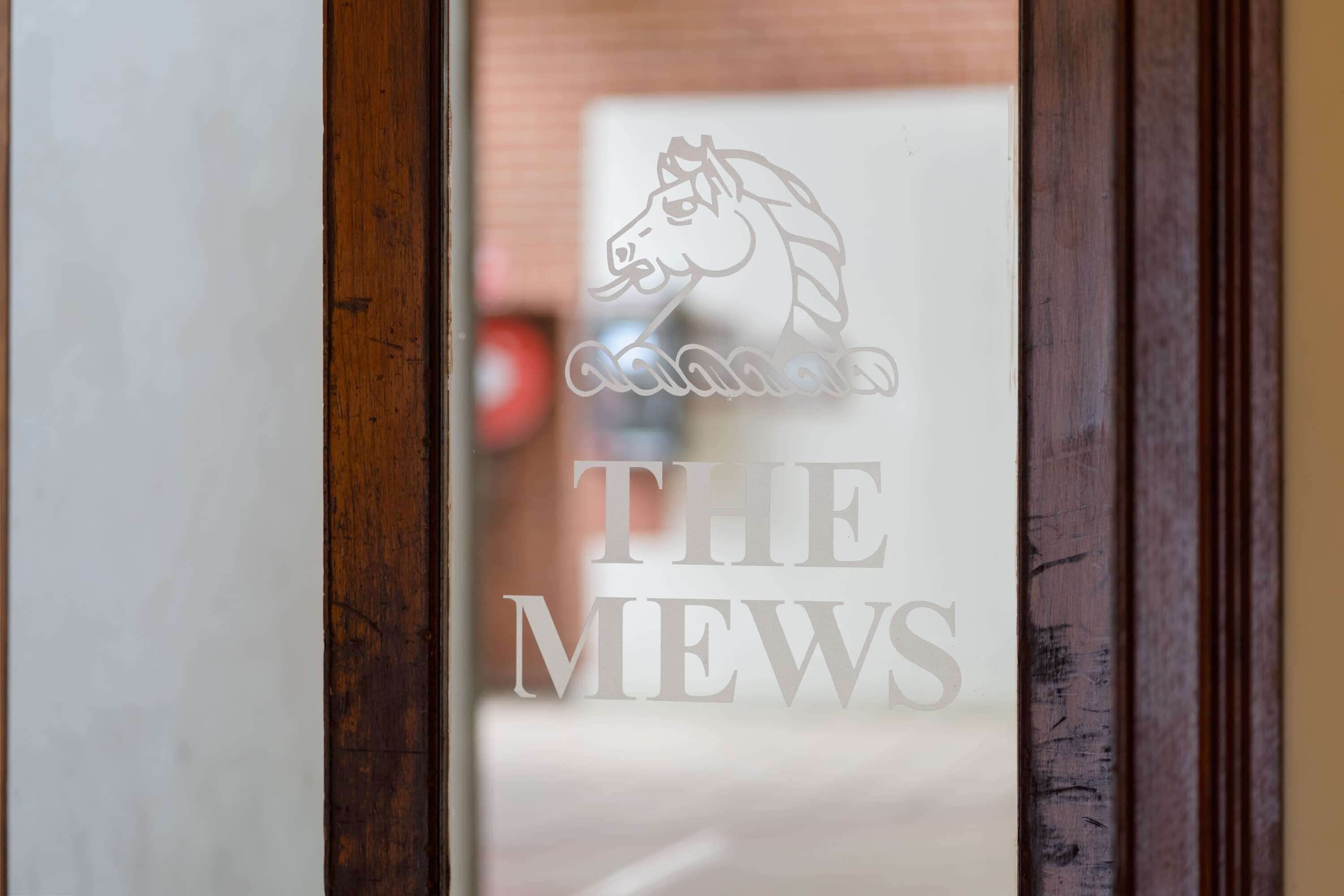 Een deur met een paardenlogo en de tekst 'THE Mews'.
