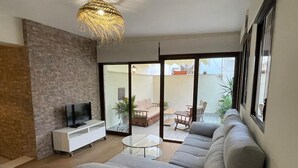 A modern living room with a large sofa, a TV on a white cabinet, and a dining area with a table and chairs. - Casa Terraza Judería: Spacious History-Filled Retreat with Private Terrace in Córdoba's Jewish Quarter (Córdoba)