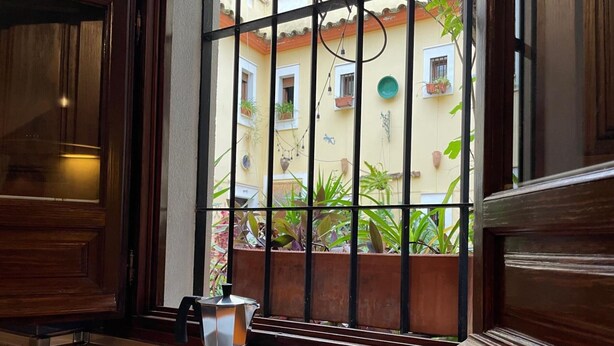 A coffee station with two cups and a pot on a tray, a window with a view of a courtyard with plants and buildings. - Casa Terraza Judería: Spacious History-Filled Retreat with Private Terrace in Córdoba's Jewish Quarter (Córdoba)