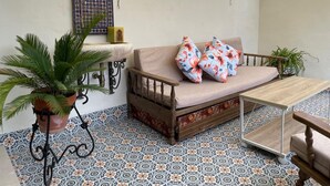 A cozy seating area with a sofa, two potted plants, and a patterned floor. - Casa Terraza Judería: Spacious History-Filled Retreat with Private Terrace in Córdoba's Jewish Quarter (Córdoba)