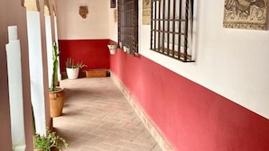 Ein Gang mit roter Wand, einem vergitterten Fenster und Blumentöpfen.