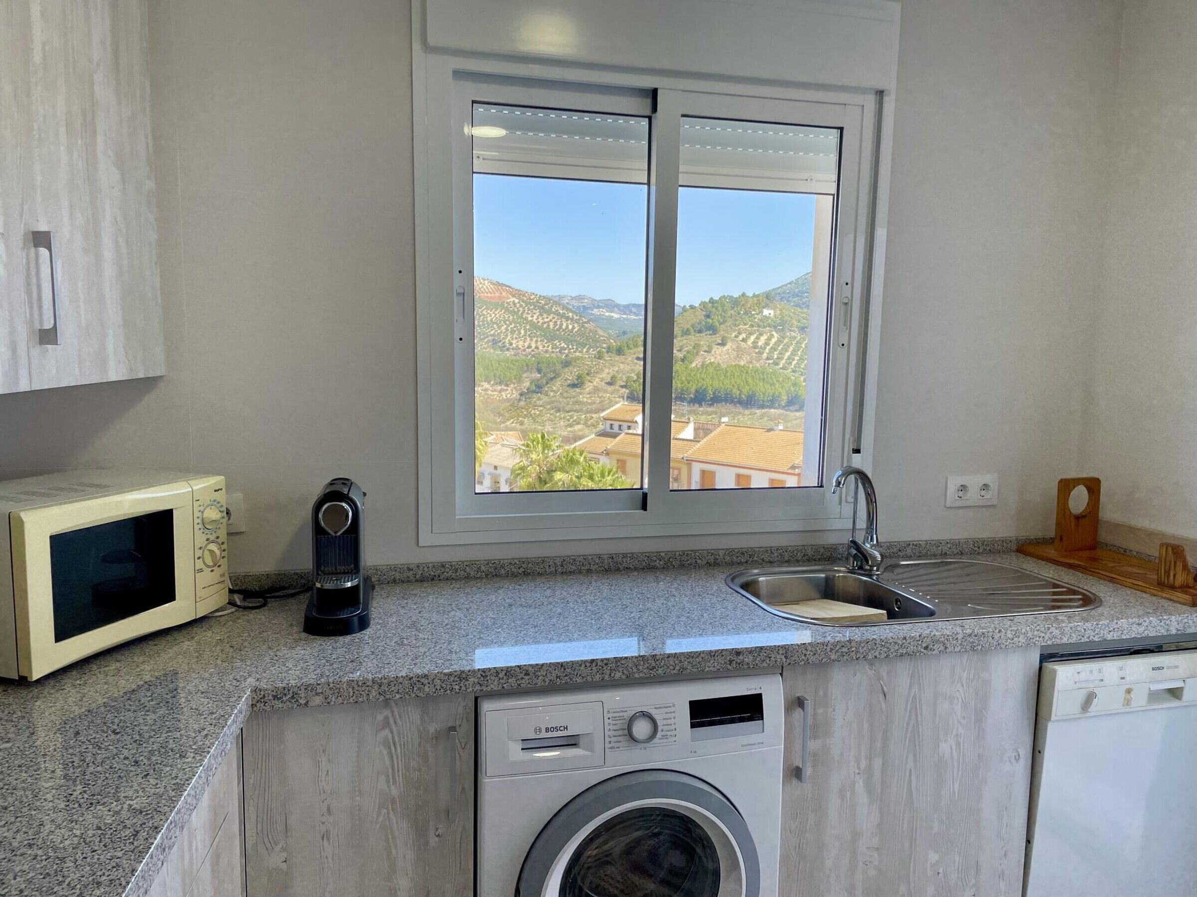 A kitchen with a built-in washing machine, a microwave, and a sink.