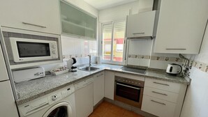 Eine kleine Küche mit Mikrowelle, Backofen, Spüle und Waschmaschine.