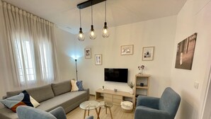 A modern living room with a sofa, two armchairs, a coffee table, and a TV. - Charming New Apartment in Historic Córdoba, Walk to Top Attractions (Córdoba)