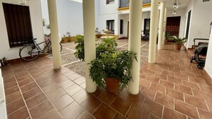 A spacious courtyard with tiled flooring, potted plants, and a bicycle. - Charming New Apartment in Historic Córdoba, Walk to Top Attractions (Córdoba)
