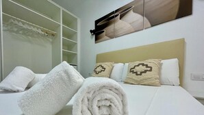 A neatly made bed with white linens and two rolled towels. - Charming New Apartment in Historic Córdoba, Walk to Top Attractions (Córdoba)