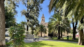 A park with a fountain, benches, and a building with a tower in the background. - Charming New Apartment in Historic Córdoba, Walk to Top Attractions (Córdoba)