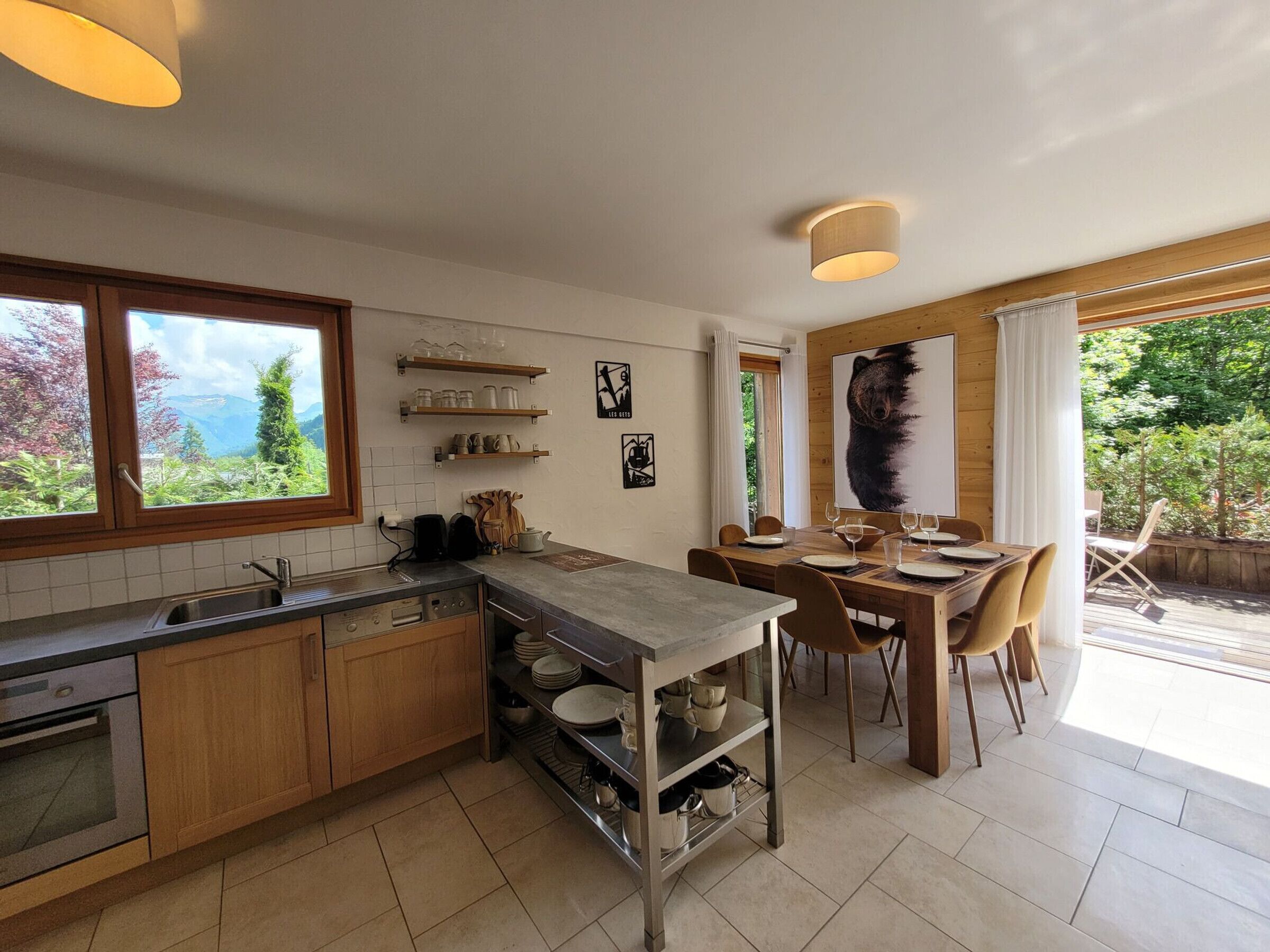 A modern kitchen with wooden cabinets, a built-in oven, and a dining area with a table and chairs.