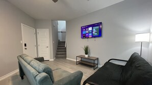 Una sala de estar con un sofá, una mesa de centro y un televisor montado en la pared.