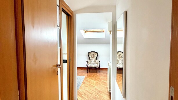 Un couloir au sol en bois, une porte portant l’inscription « 502 », et une chaise au loin.
