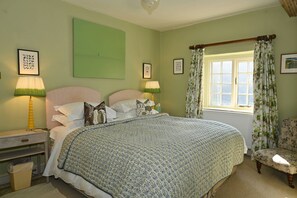 A bedroom with a bed, two bedside lamps, a window with curtains, a chair, and framed pictures on the wall. - Idyllic country detached cottage sleeping 8 guests with access to an award winning wellbeing resort (Yorkshire Dales)