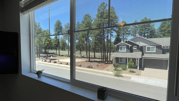 A room with a large window overlooking a residential area with houses and trees. - Windtree Hideaway! Trees, hiking, minutes downtown (Flagstaff)