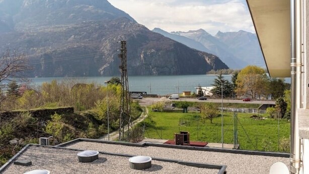 Une vue depuis une chambre d’hôtel donnant sur un lac, avec des montagnes en arrière-plan.