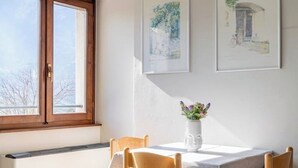 Un coin repas avec une table dressée pour deux personnes, un vase rempli de fleurs et des œuvres d’art encadrées accrochées au mur.