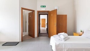 Une chambre d’hôtel avec un lit, une table de chevet, une armoire et un panneau indiquant la sortie.