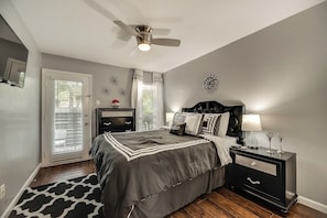 A bedroom with a bed, nightstand, dresser, ceiling fan, and decorative wall pieces. - I48-1 - Apt|Patio|11mi to Convention Ctr|Sleeps 2 (Irving)