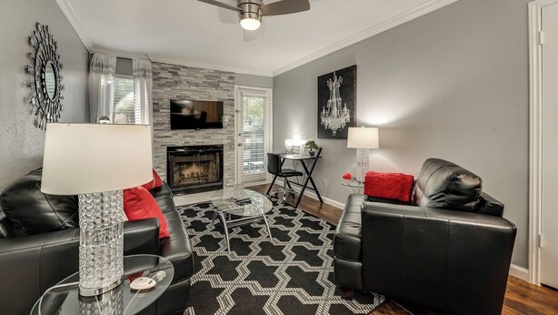 A modern living room with a fireplace, leather sofas, a glass coffee table, and a patterned rug. - I48-1 - Apt|Patio|11mi to Convention Ctr|Sleeps 2 (Irving)
