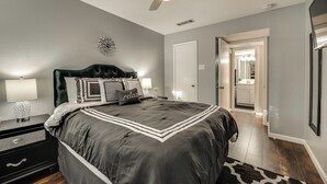 A bedroom with a large bed, two bedside tables with lamps, a ceiling fan, and a door leading to another room. - I48-1 - Apt|Patio|11mi to Convention Ctr|Sleeps 2 (Irving)